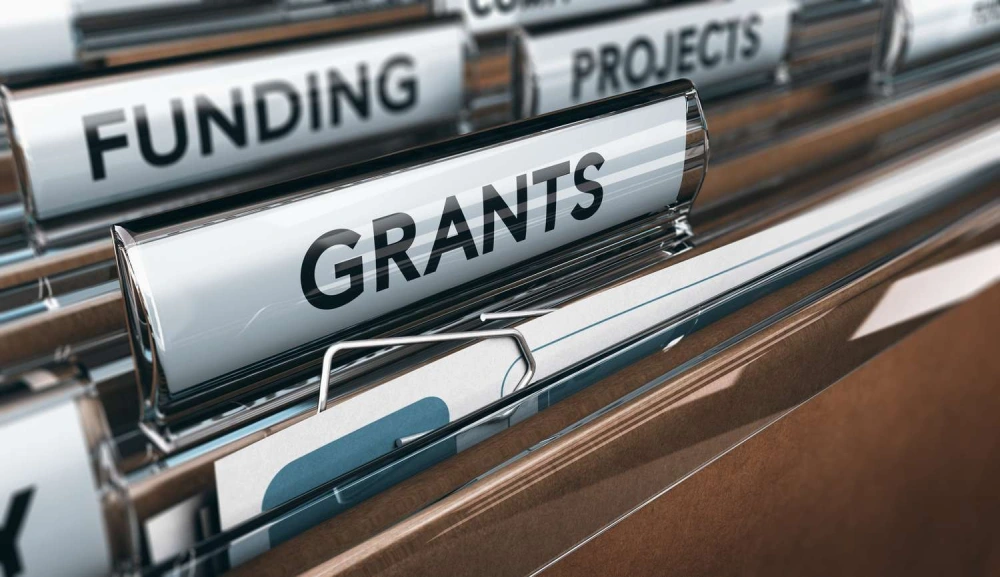 A close-up of a file cabinet reveals a clearly labeled “Grants” folder among folders for funding and projects, symbolizing the organization and accessibility of financial resources in conservation work.