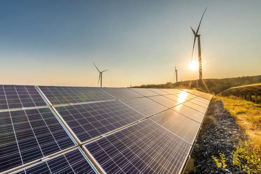 Solar panels and wind turbines generating renewable energy at sunrise or sunset 